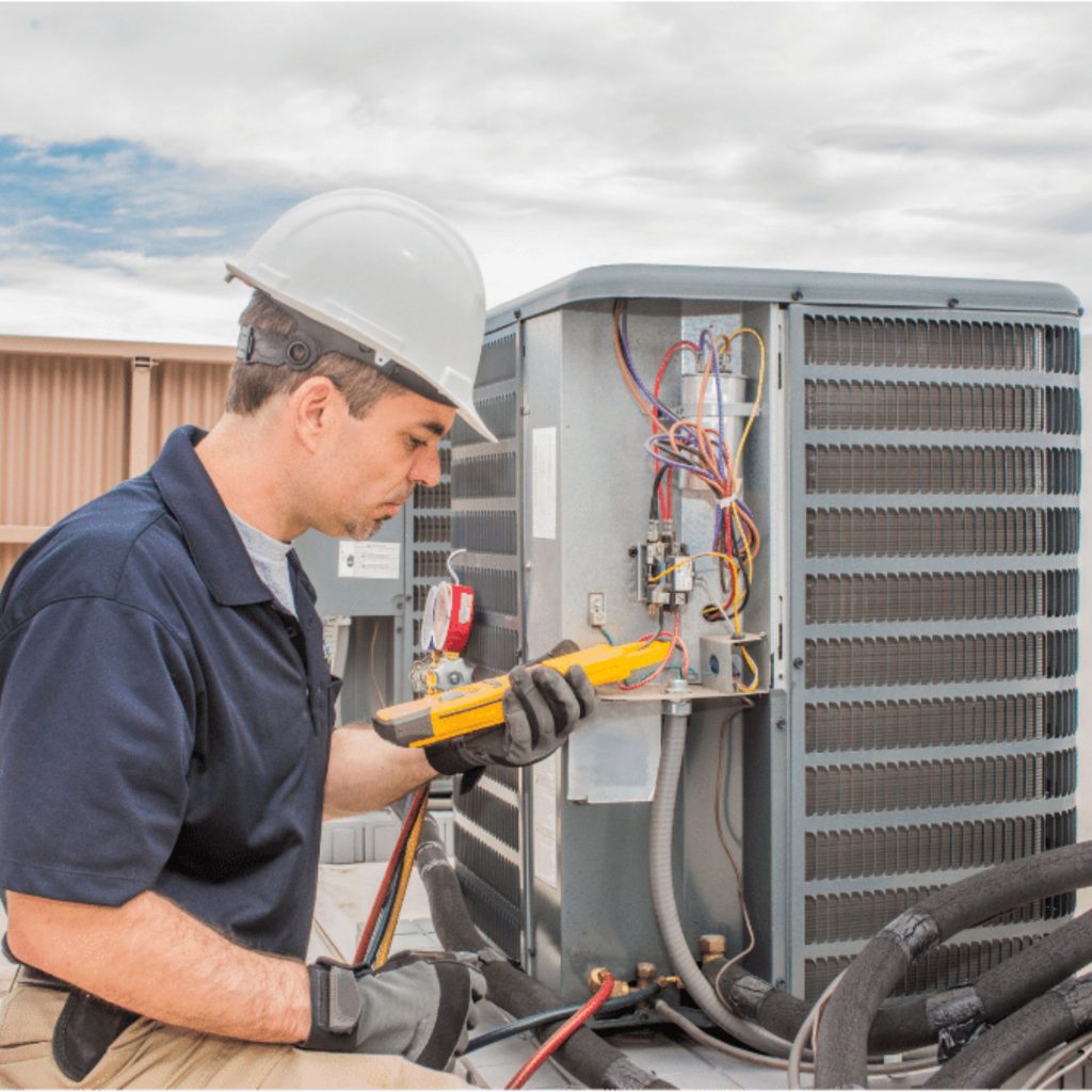 man in hardhat inspecting rooftop HVAC unit